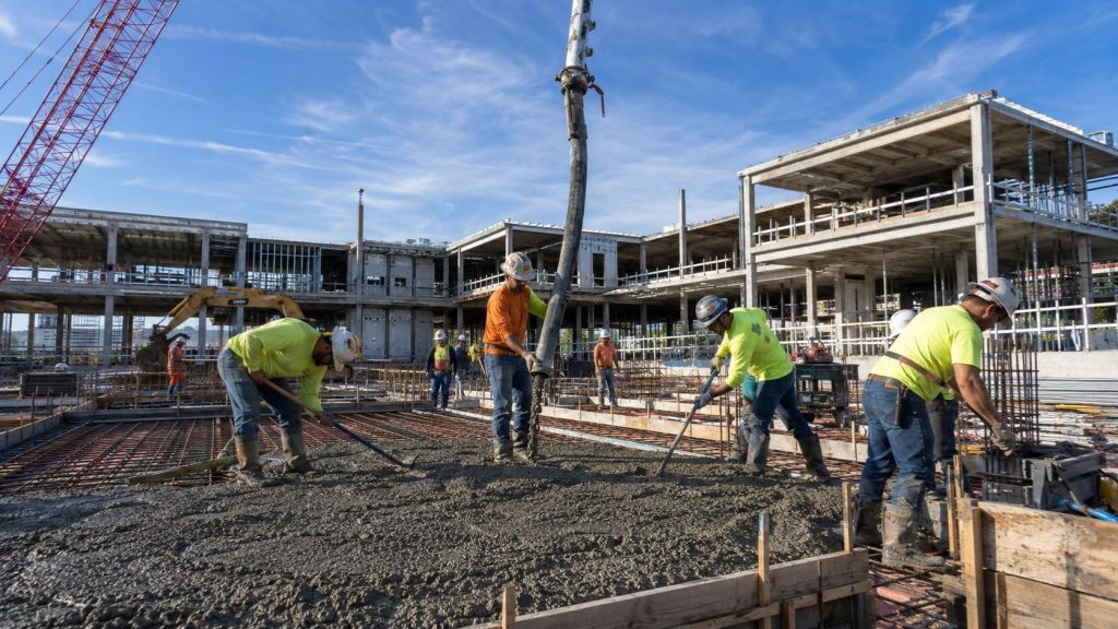 Commercial construction project in Tallahassee Florida with concrete placement crews, reinforced slab installation, and active building development